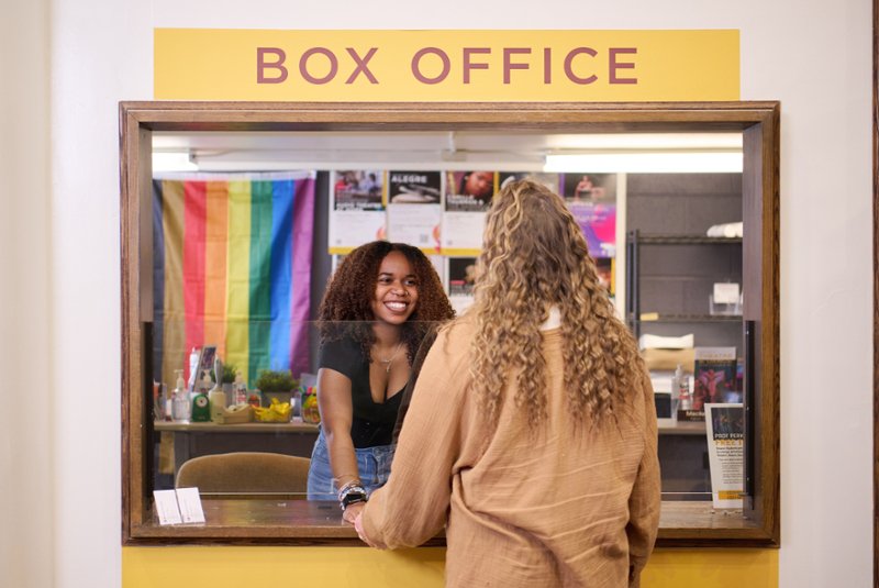 box office employee assisting a woman at the box office window