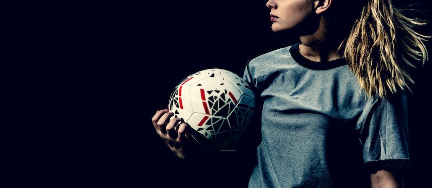 profile of a teenage girl holding a soccer ball, wearing a jersey, hair in ponytail