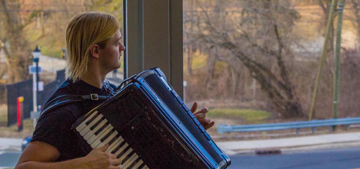 student playing the accordion looking out the window 