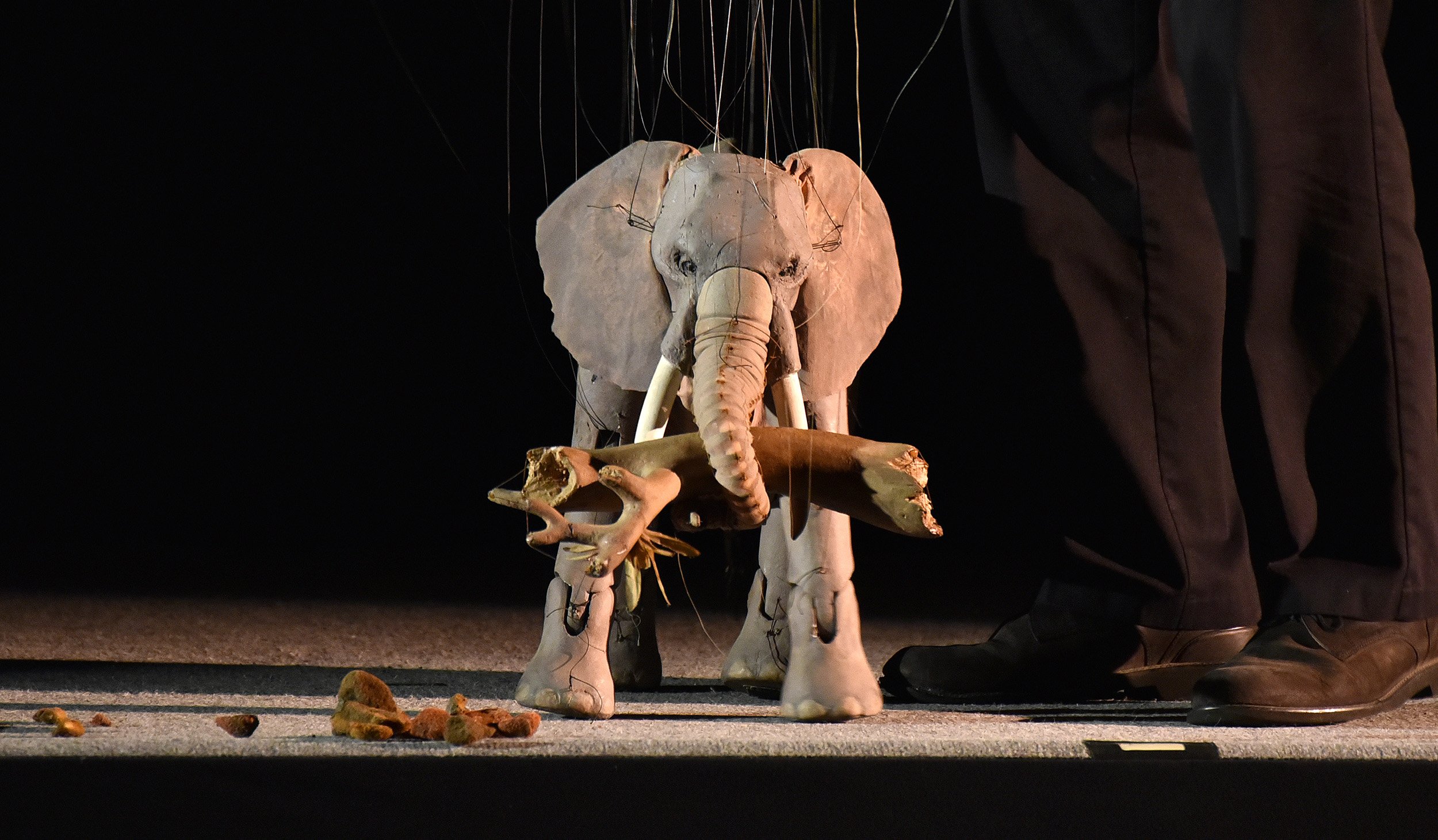 Marionette puppet of an elephant holding branches in its trunk.