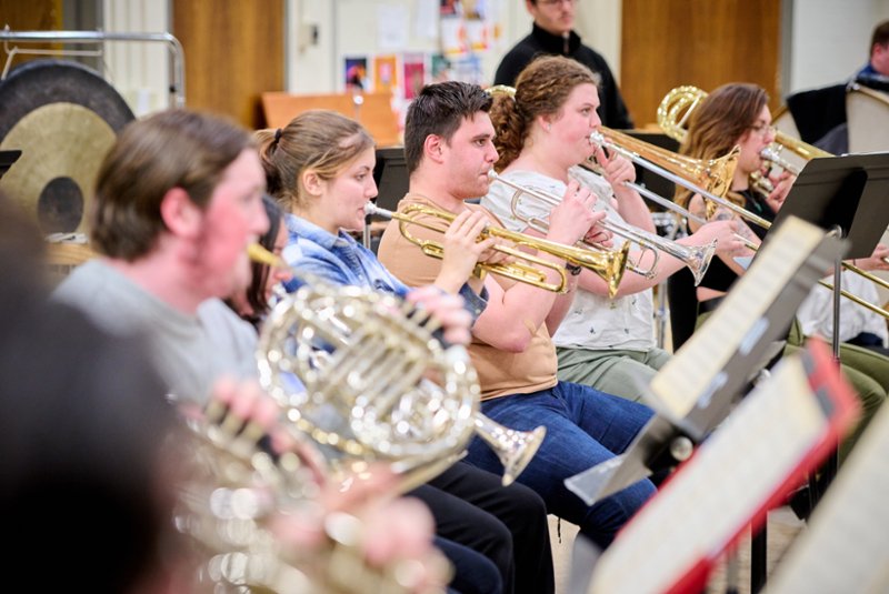 5 students playing brass instruments in a classroom